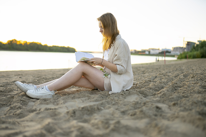 Woman reading book beach at sunset, by Vyacheslav Chistyakov