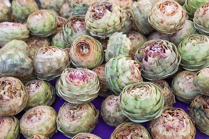 Colorful freshly picked selection of organic artichokes on display at the farmers market, by Andy Dean