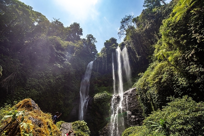 The Sekumpul waterfall, a large waterfall in the middle of the jungle that plunges into a deep green gorge. Trees and tropical plants at Bali's highest waterfall, by Jan Wehnert