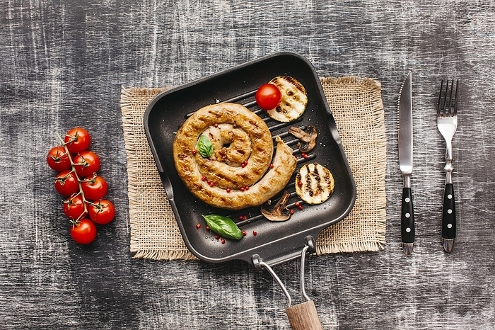 Spiral yummy grilled sausages pan with vegetable textured background, by Oleksandr Latkun