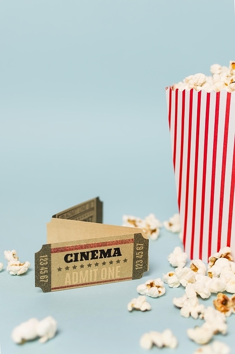 Cinema tickets with popcorns against blue backdrop, by Oleksandr Latkun