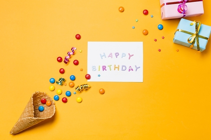 Streamers gems waffle with happy birthday paper against yellow background, by Oleksandr Latkun