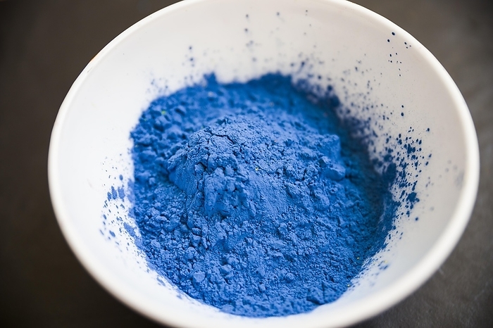 Blue powder inside white bowl black background, by Oleksandr Latkun