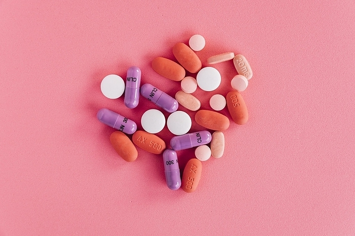 Overhead view colorful pills pink background, by Oleksandr Latkun