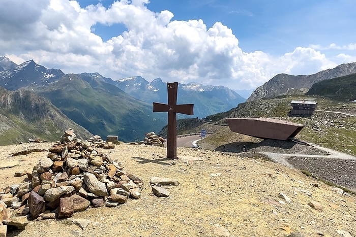Austria On the left pile of stacked stones, in the middle behind it small cross on a hill, in the background pass museum on 2509 metres high Timmelsjoch Passo Rombo rises from Austrian territory on the right to the left in the air of Italian territory, Alps, Tyrol, South Tyrol, Austria, Italy, Europe, by Frank Schneider