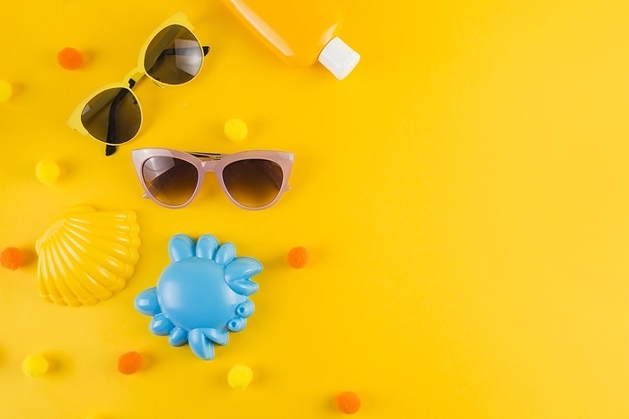 Overhead view sunglasses sunscreen lotion bottle scallop crab toy yellow backdrop, by Oleksandr Latkun
