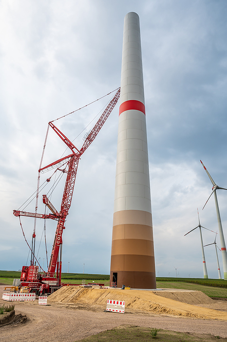 Construction site of a wind turbine, crane next to the tower of the wind turbine, completed wind turbines in background, low angle view, cloudy day Construction site of a wind turbine, crane next to the tower of the wind turbine, completed wind turbines in background, low angle view, cloudy day, by Zoonar Markus Beck