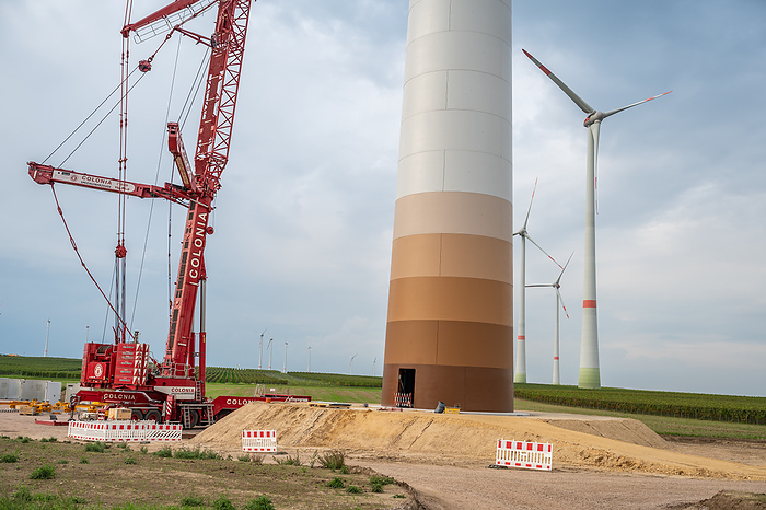 Construction site of a wind turbine, crane next to the tower of the wind turbine, completed wind turbines in background, low angle view, cloudy day Construction site of a wind turbine, crane next to the tower of the wind turbine, completed wind turbines in background, low angle view, cloudy day, by Zoonar Markus Beck