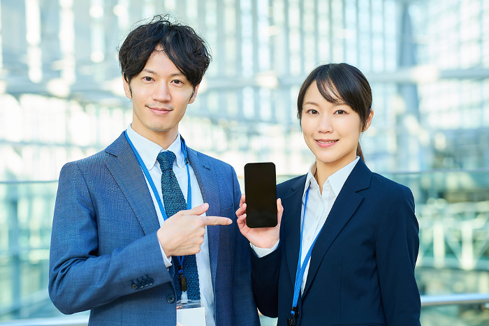 Japanese man and woman in suits showing smartphone screens (People)