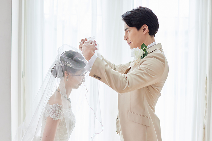 Japanese groom raising the bride's veil.