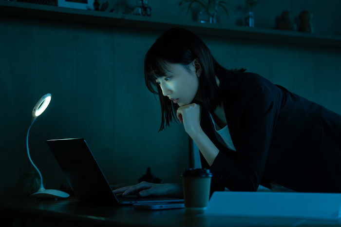 Japanese businesswoman using a computer in a dark room.