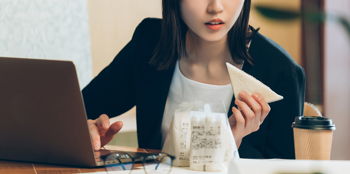 Busy Japanese businesswoman working over a sandwich