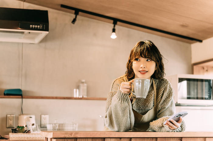 Japanese woman drinking a drink at the kitchen counter (People)