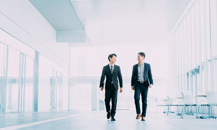 Two Japanese businessmen walking in an office (People)