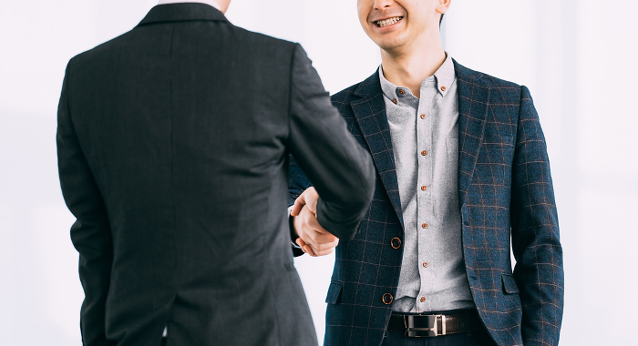 Two Japanese businessmen shake hands.