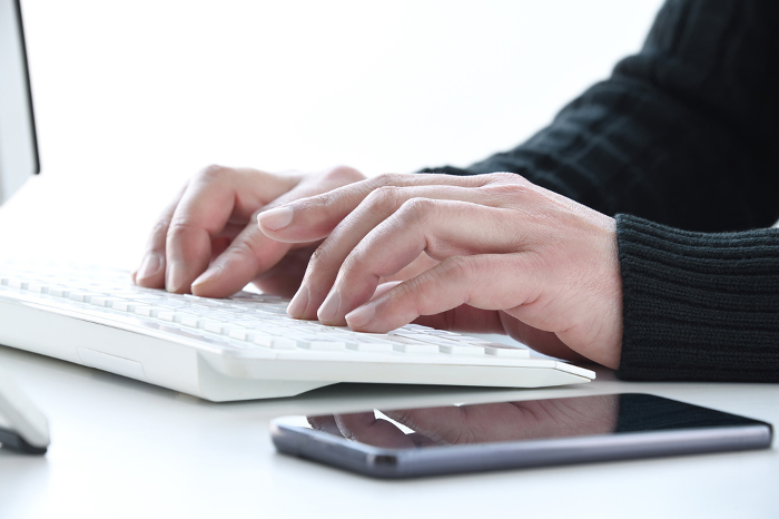 Hand of a man in plain clothes working on a computer