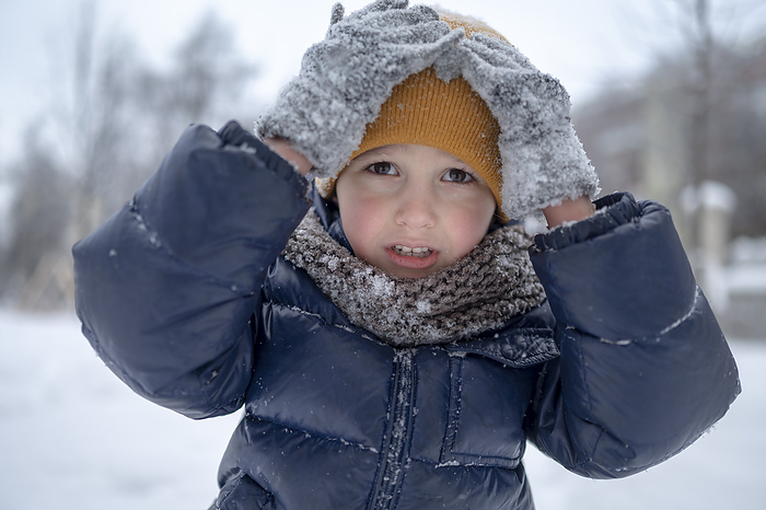Boy touching yellow knit hat in winter