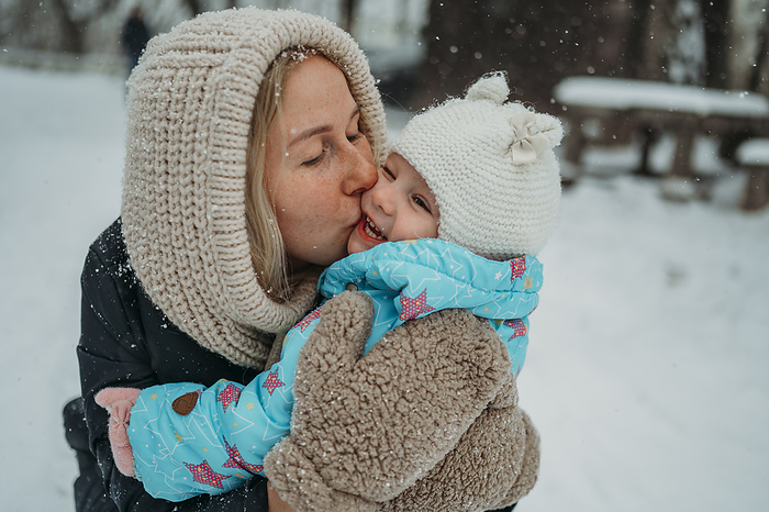 Happy mother kissing daughter in winter