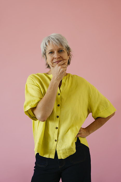 Woman with hand on chin against pink background