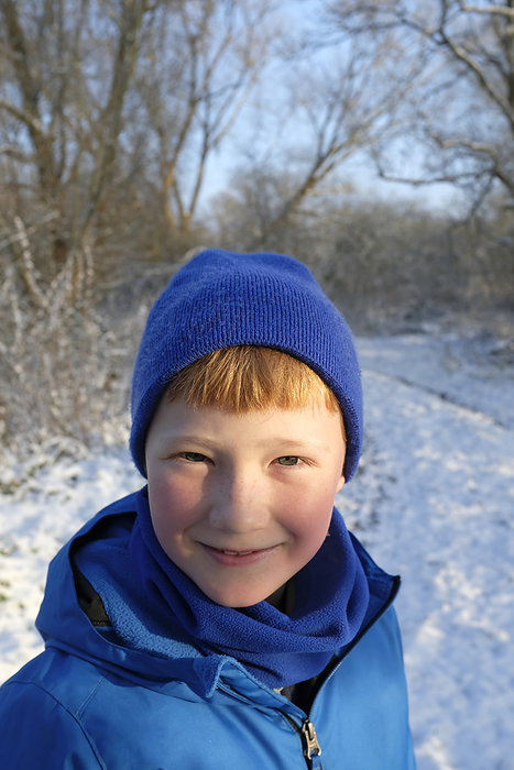 wintertime Smiling boy wearing knit hat in winter forest