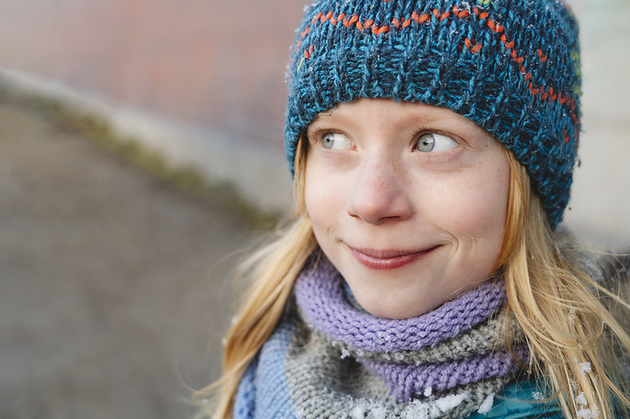 Smiling girl with blond hair wearing knitted hat