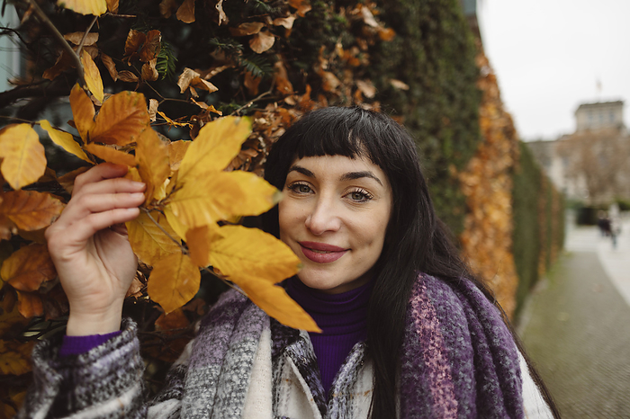 Smiling woman with autumn leaves in park