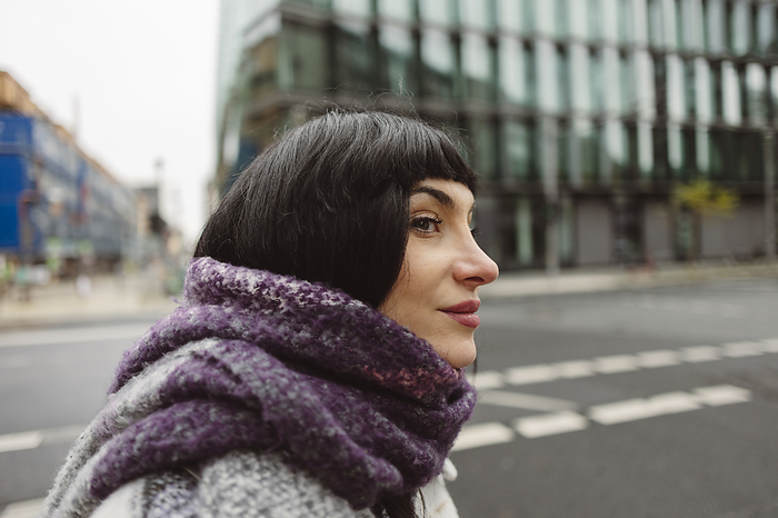 Thoughtful woman with scarf around neck on street