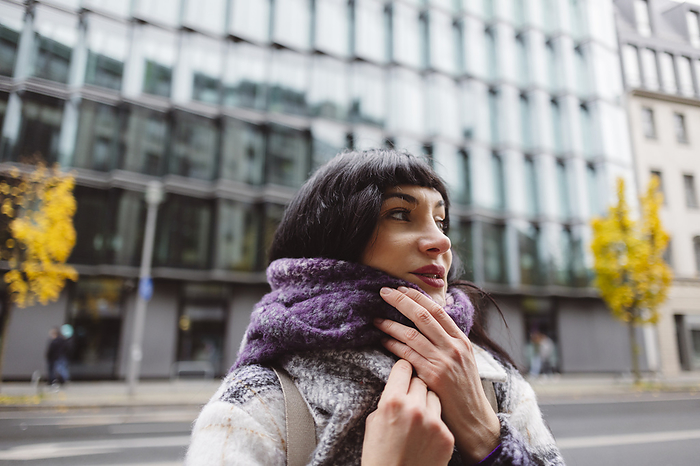 Contemplative woman with scarf around neck on street