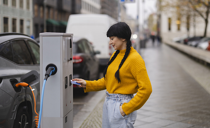 Woman making payment through credit card at electric vehicle charging station