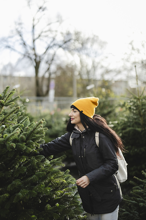 Woman wearing knit hat and buying fir tree