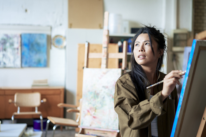 Thoughtful painter painting on canvas in art studio