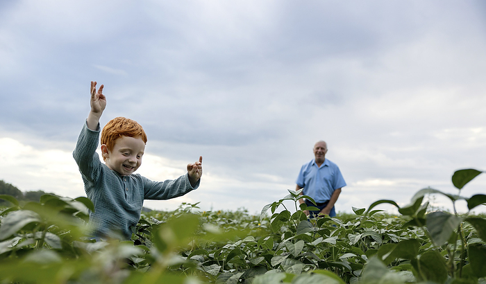 Happy boy playing with grandfather in field