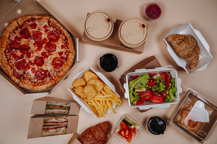 Fast foods and salad with pizza against beige background