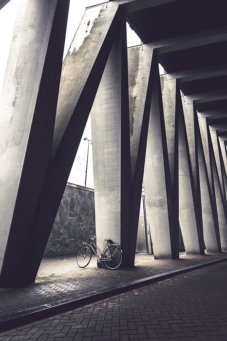 Bicycle laying over concrete structure Bicycle near architectural columns