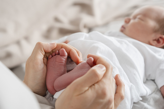 Mother holding newborn son's feet in hand