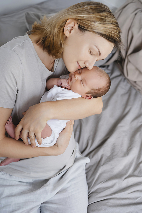 Loving mother embracing newborn son in arms