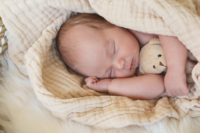 Cute baby boy sleeping with stuffed teddy bear toy
