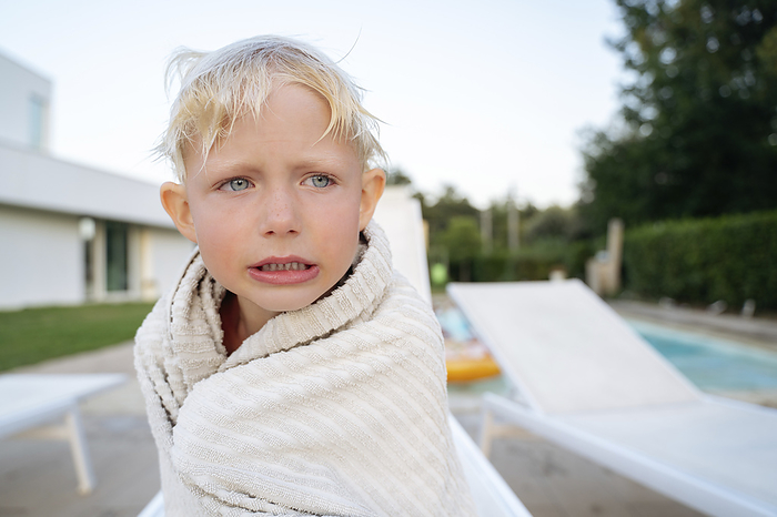Blond boy shivering wrapped in towel