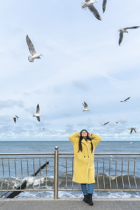 Carefree woman having fun near sea with seagulls flying in mid-air