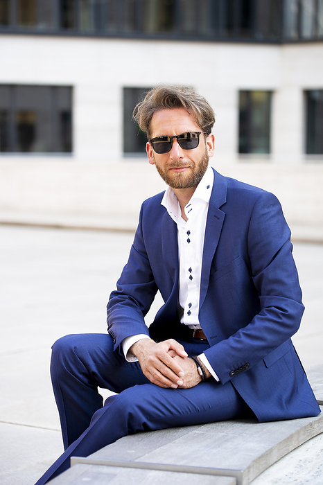 Businessman wearing sunglasses and sitting in the city