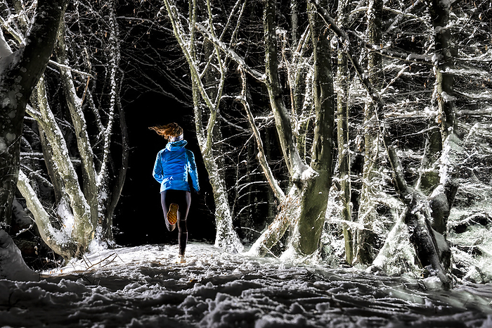 Woman running in winter forest at night