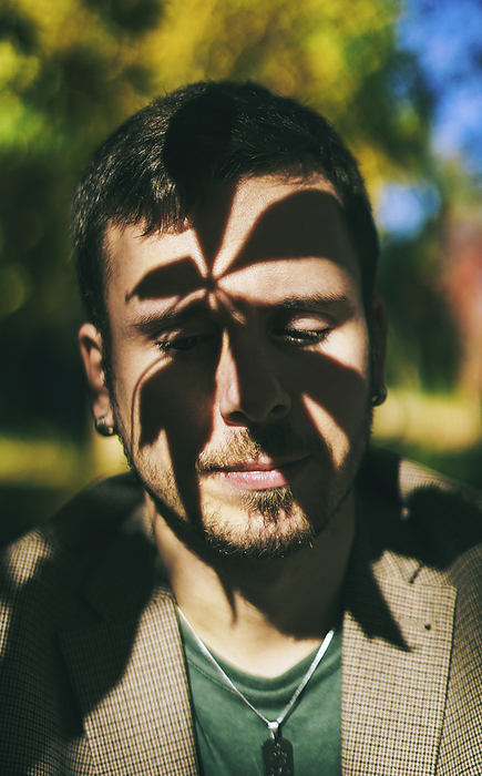 Sad man with shadow of leaves on face