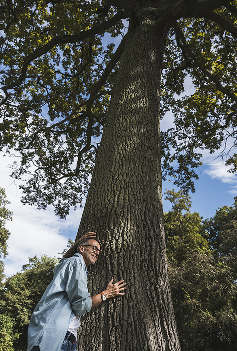 Senior man leaning on tree in park