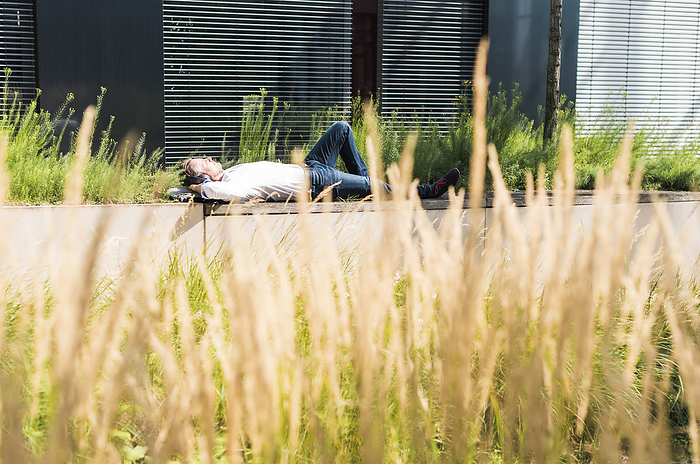 Businessman relaxing near building on sunny day