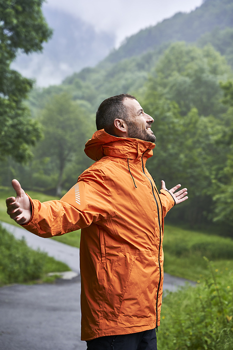 Happy man wearing orange jacket in front of Pyrenees mountain