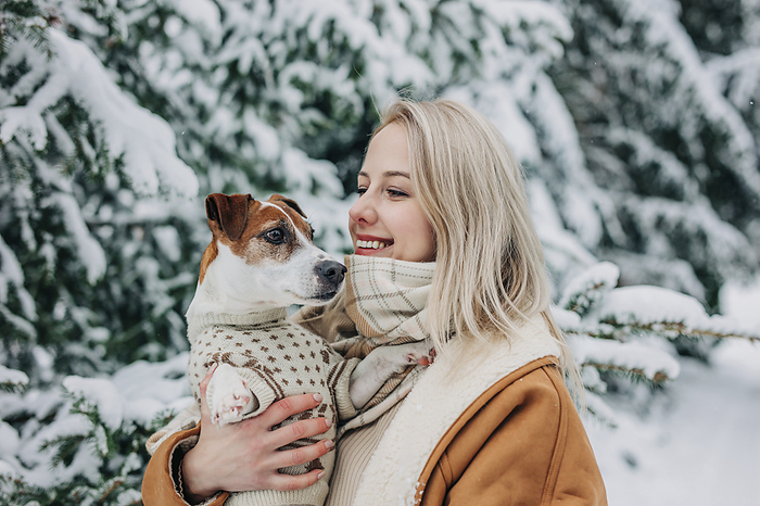 Happy woman with blond hair holding dog in arms