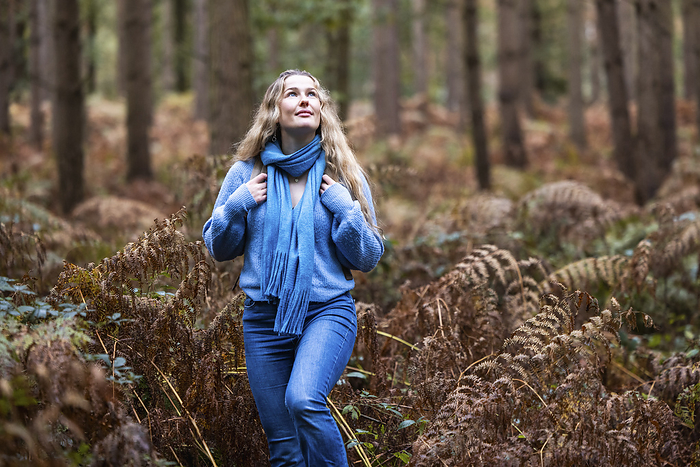 Smiling blond woman walking near plants in Cannock chase forest