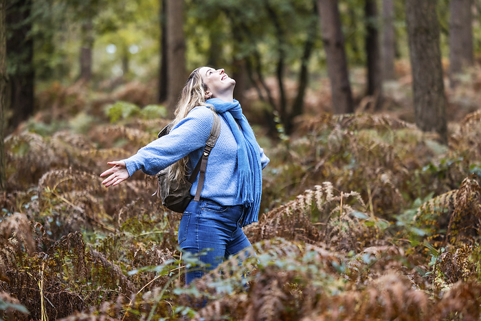 Carefree woman with arms outstretched standing in Cannock chase forest