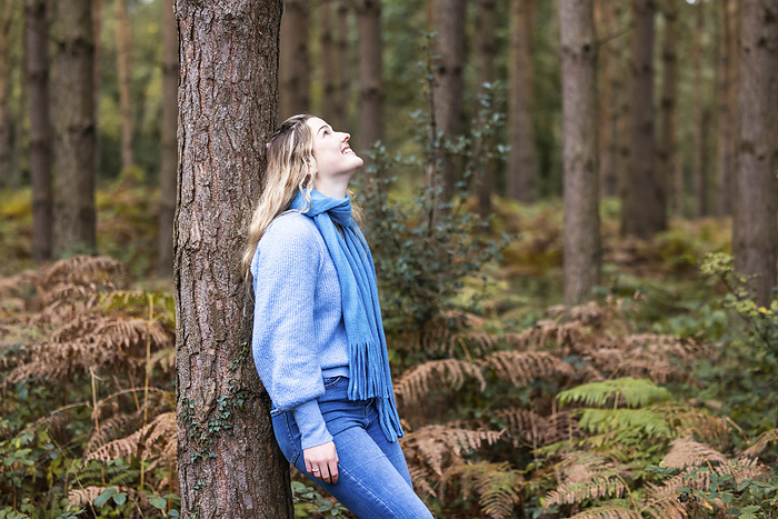 Happy woman leaning on tree in Cannock chase forest