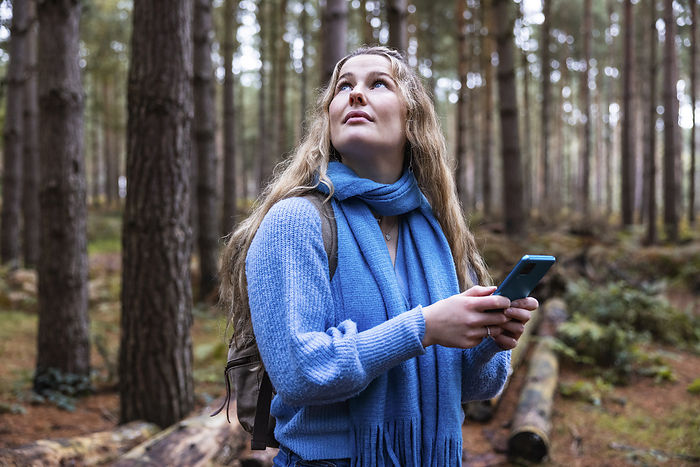 Thoughtful woman with smart phone in Cannock chase forest